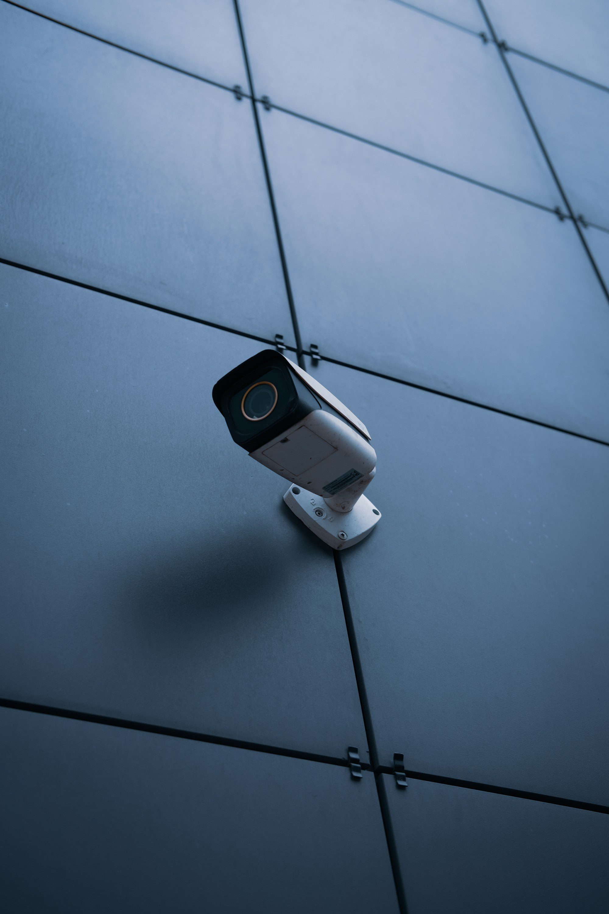 A bullet camera mounted on a blue-grey panelled facade
