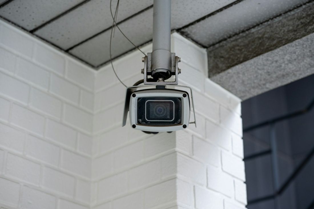 A camera mounted under a white brick soffit
