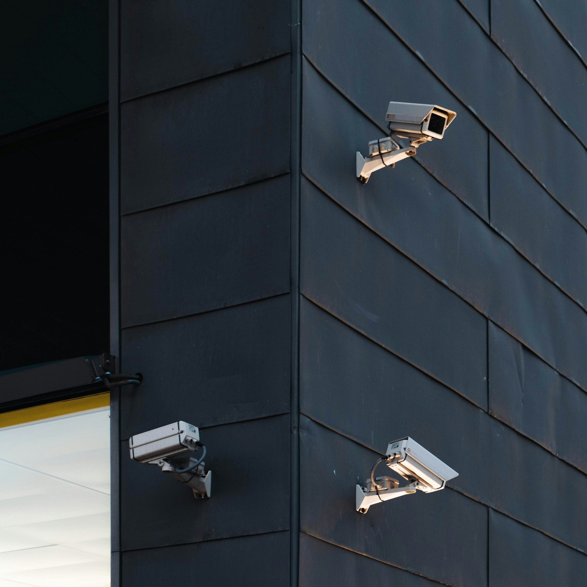 Three cameras covering the corner of a dark building