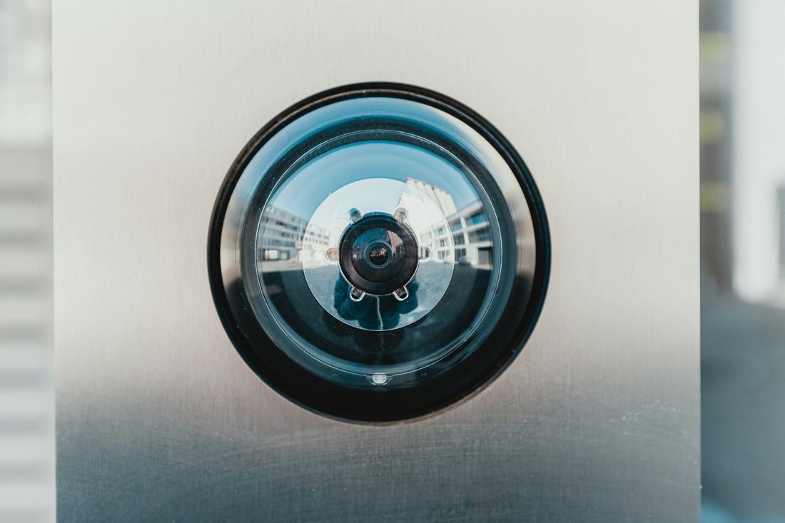 Close-up of a camera lens set into a brushed metal wall
